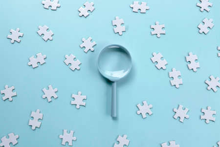 Magnifying Glass Over Jigsaw Puzzle Pieces for Detailed Inspectionの写真素材