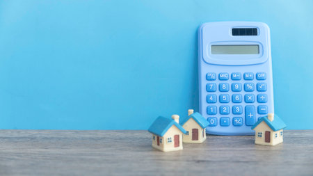 Toy house and calculator against a blue background with copy space.の写真素材