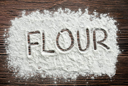 Flour written on a sprinkled flour powder on the table.の写真素材
