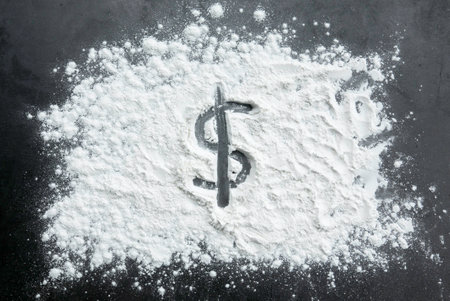 Dollar sign on sprinkled flour powder on a table.の写真素材
