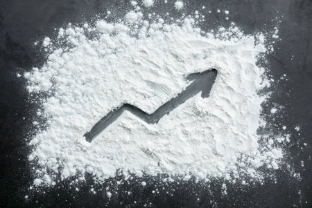 ascending arrow drawn on a sprinkled flour powder.の写真素材