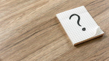 Question Mark on Graph Paper Notepad on Wooden Surface