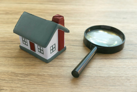 House Model and Magnifying Glass on Wooden Surface - Real Estate Conceptの写真素材