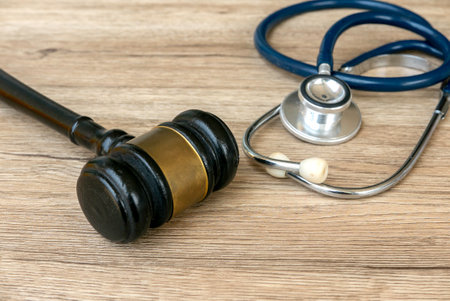 Gavel and Stethoscope on Wooden Surface Representing Legal and Medical Professionsの写真素材