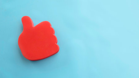 Red Thumbs Up Hand Gesture on Light Blue Background.の写真素材