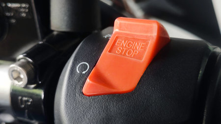 Red Engine Stop Switch on Black Surface with Rotational Arrow Symbol.