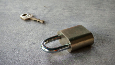 padlock and a key lay on a gray surfaceの写真素材