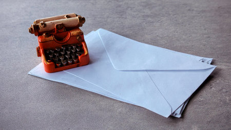 Miniature typewriter on a stack of white envelope.