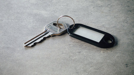 Metallic Key with Black Plastic Key Tag on Gray Surface