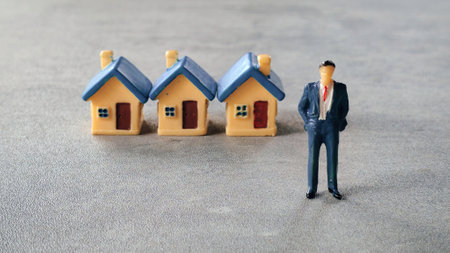 A businessman standing in front of a row of miniature house.