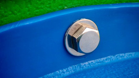 Close-Up of a Metallic Hexagonal Bolt and Washer Secured to a Blue Painted Surfaceの写真素材