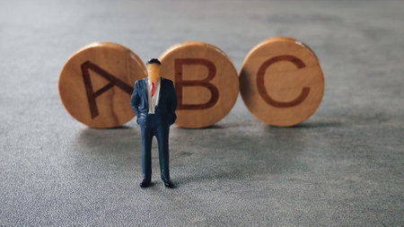 Miniature Figurine in Suit Standing Near Alphabet Blocks "ABC"の写真素材