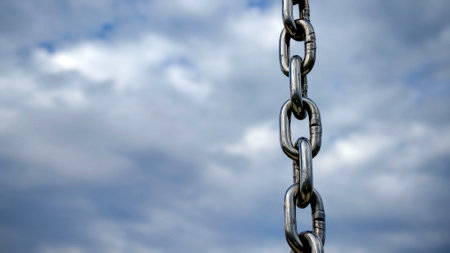 Close-Up of Interlinked Metal Chain Links Against a Cloudy Background