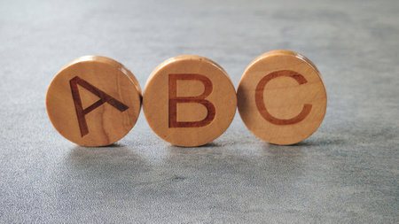 Wooden Alphabet Blocks A, B, and C on a Gray Surface
