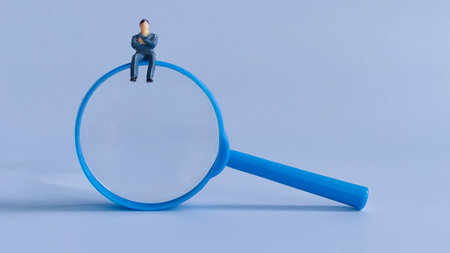 Miniature Businessman Sitting on Magnifying Glass Symbolizing Analysis, Focus, and Strategic Decision-Makingの写真素材