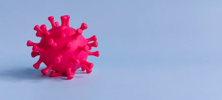 Red Virus Model on Blue Background with Copy Space Representing Disease, Infection, and Health Crisisの写真素材