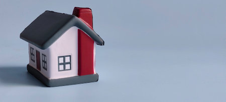 House Model Isolated on Blue Background with Copy Space Representing Real Estate, Home Ownership, and Property Investmentの写真素材