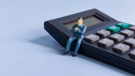 Miniature Businessman Sitting on a Calculator