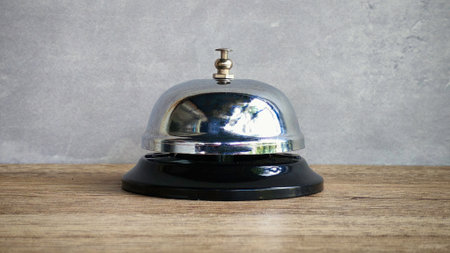 Classic Chrome Service Bell on Wooden Table, Signifying Hospitality, Customer Service, and Assistanceの写真素材