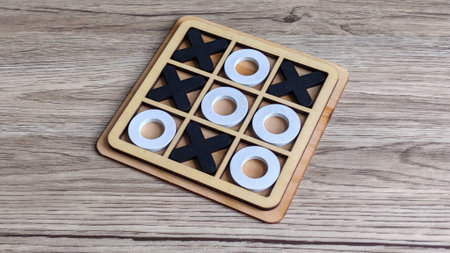 Wooden Tic-Tac-Toe Game with X and O Pieces on Table, Symbolizing Strategy, Games, and Competitionの写真素材
