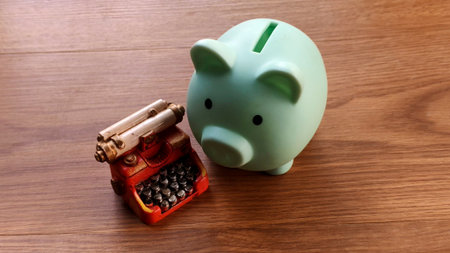 Miniature Typewriter and Piggy Bank on Wooden Tableの写真素材