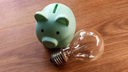 Piggy Bank and Light Bulb on Wooden Tableの写真素材