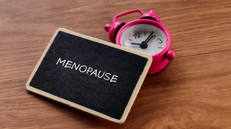 Menopause Concept with Pink Alarm Clock and Blackboard
