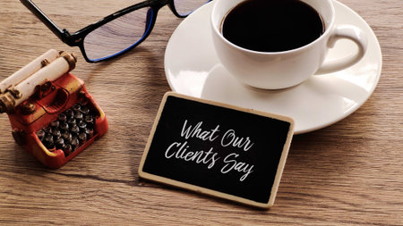 Top-down view of a wooden desk with a small chalkboard displaying What Our Clients Say, alongside a...