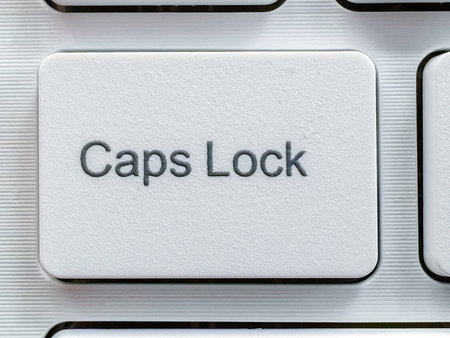 Close-up of a White Caps Lock Key on a Modern Silver Keyboard.