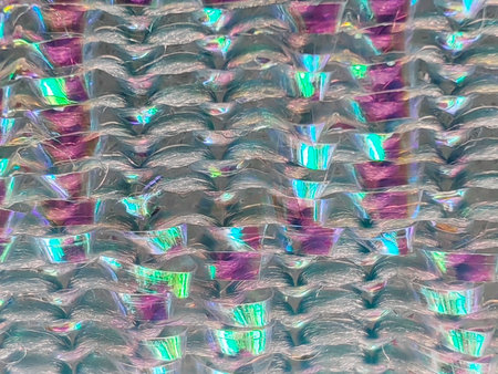 Close-up macro photo of a shimmering, textured metallic-sheen kitchen scrubber, showing an abstract pattern of interwoven fibers with iridescent colors.の写真素材
