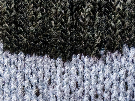 Detailed macro shot of a two-tone knitted fabric, featuring a distinct division between a dark,...