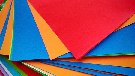 Stack of multicolored origami papers on a gray stone or concrete background.