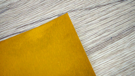 Metallic gold paper sheet on wooden table, elegant background with copy space