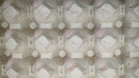 Close-up of a brown cardboard egg carton or crate, with a textured background.