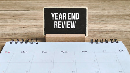 Year End Review or Business Performance Concept: Chalkboard Sign on a Desk Calendar on a Wood Table.