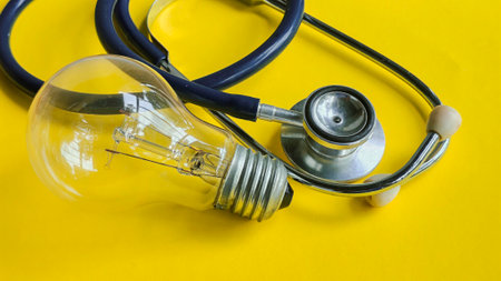 Stethoscope and light bulb on a yellow background, representing healthcare innovation, medical ideas, and the concept of finding a diagnosis or cure.の写真素材