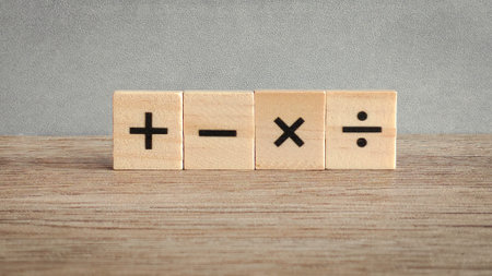 Four fundamental math operation signs on wooden blocks: addition, subtraction, multiplication, and division for education and business concepts.の写真素材