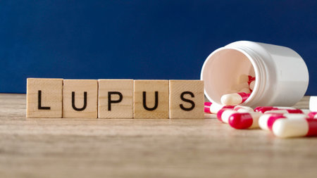Wooden Blocks Spelling Lupus with Spilled Medicine Capsules for Autoimmune Disease Conceptの写真素材