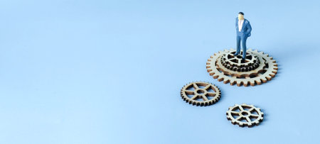 Corporate Hierarchy and Business System Strategy: Businessman Figure and Disconnected Wooden Gearsの写真素材