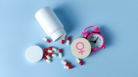 Women's Health, Hormone, and Menstrual Cycle Timing Concept: Female Symbol, Alarm Clock, and Medicineの写真素材