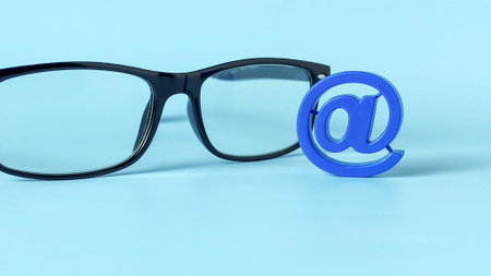 Black-Framed Glasses and Blue At Symbol Representing Email Communication, Digital Vision, and Online Clarityの写真素材