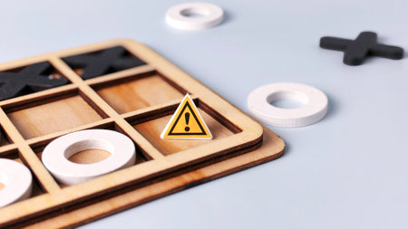 Strategic Business Risk and Caution: Warning Sign Placed on a Wooden Tic-Tac-Toe Game Boardの写真素材