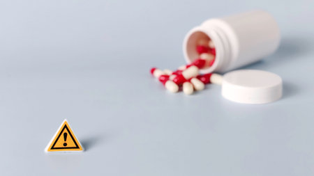 Caution Sign with Spilled Red and White Pills from Bottle Representing Drug Overdose, Medication Side Effects, and Pharmaceutical Riskの写真素材