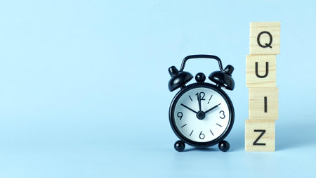 Wooden Blocks Spelling 'QUIZ' with an Alarm Clock Above Representing Test Deadlines, Educational Assessment, and Time Pressureの写真素材