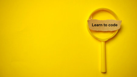 "Learn to code" essential message highlighted by a yellow magnifying glass, symbolizing the deep dive into technology and skill development.の写真素材