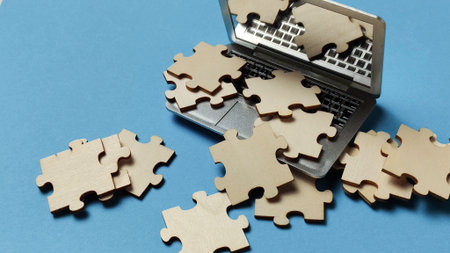Digital Puzzle Unfinished: Wooden Jigsaw Pieces Spilling Out of a Laptop Screen on a Blue Background, Representing Problem Solving, Data Analysis, and Cybersecurity Challenges.の写真素材
