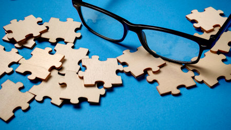 Finding the Right Perspective: Wooden Puzzle Pieces and Black Glasses on a Blue Background