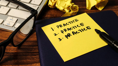 The Importance of Repetition: 'Practice' Written Three Times on a Yellow Sticky Note for Motivationの写真素材