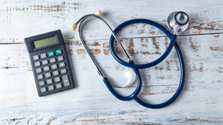 Stethoscope and Calculator on a Wooden Background: Analyzing Healthcare Costs, Medical Billing, and Financial Planningの写真素材