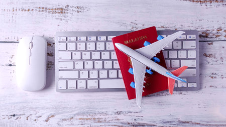 Toy Airplane and Malaysia Passport on a Computer Keyboard: Booking Online Travel, Global Business, and Holiday Planningの写真素材